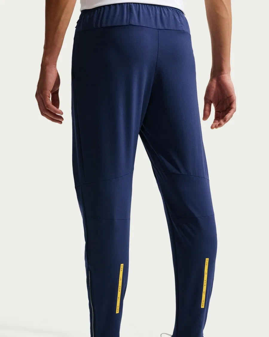 Pantalon running de Tottenham bleu marine vu de dos, bandes jaunes sur les mollets