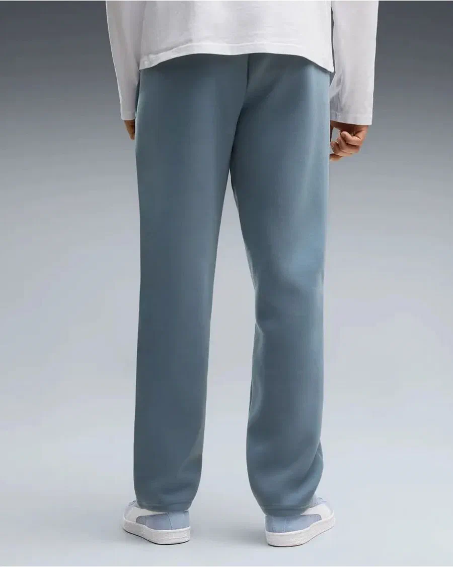 Pantalon PUMATECH Manchester City bleu gris, coupe droite, porté avec des baskets blanches