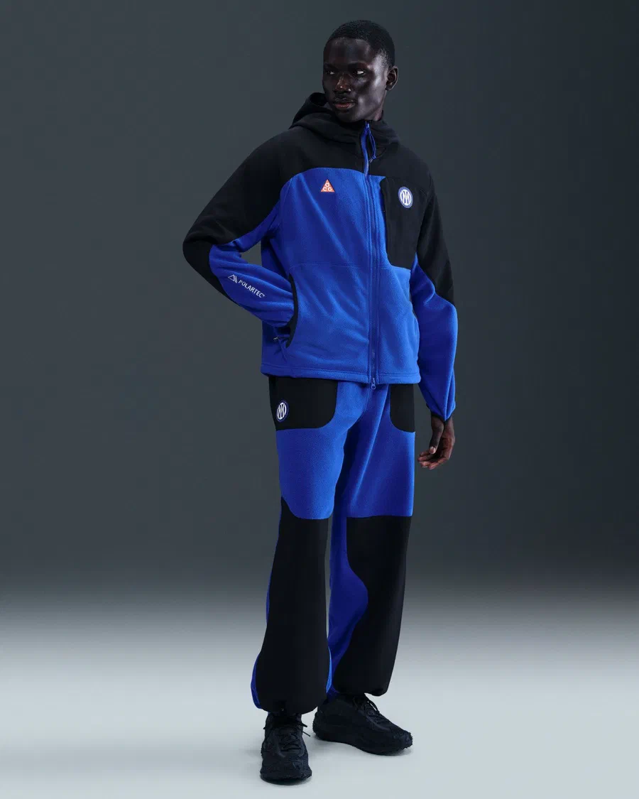 Mannequin en veste polaire bleue et noire à capuche Inter x ACG et pantalon assorti, sur fond sombre